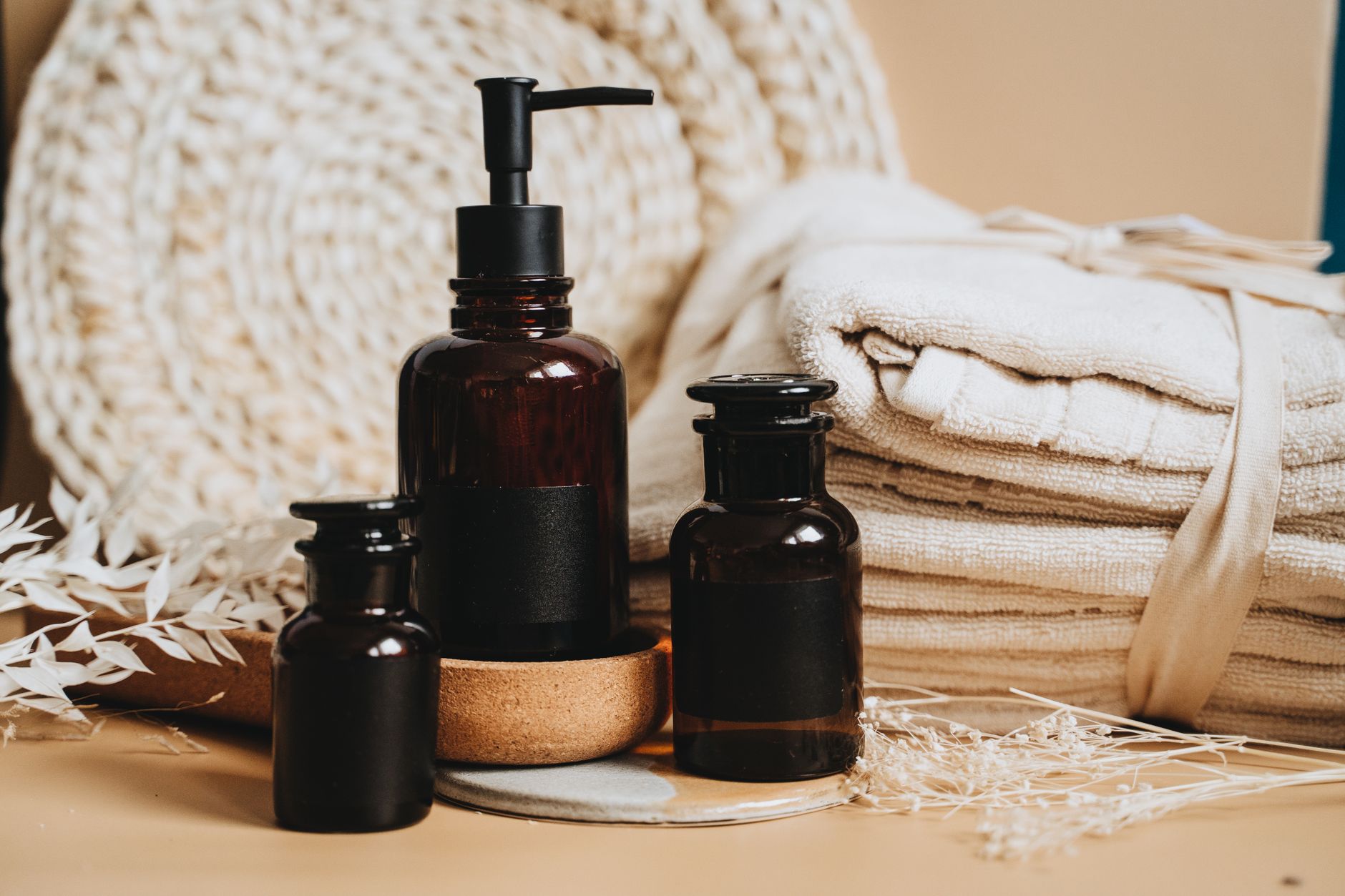 Una botellita elegante de lubricante a base de agua colocada sobre una repisa blanca de baño junto a una toalla blanca doblada, luz ambiental suave de baño, estilo limpio y fresco, fotografía de producto minimalista - Foto de Alesia  Kozik en Unsplash