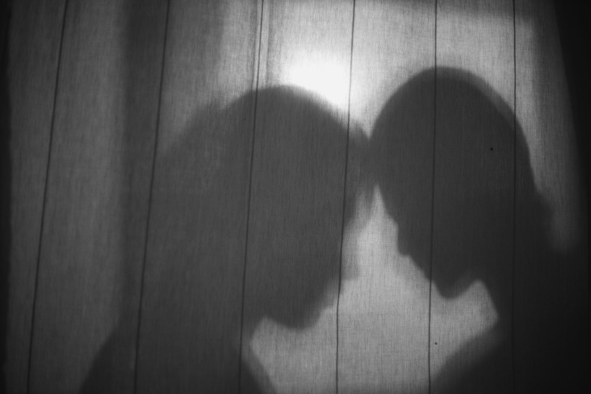 Two figures pressed against a frosted glass wall, soft diffused light filtering through, close physical contact, warm skin tones, intimate framing, portrait 9:16 orientation - Photo by Yaroslav Shuraev on Unsplash