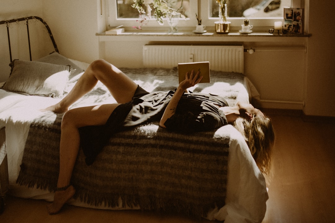 Person lying on a bed reading, relaxed soft light