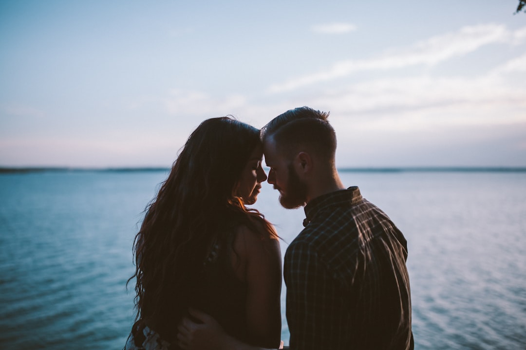 Portrait editorial shot of a couple lying facing each other on a bed, eyes open, soft low evening light, relaxed body language, forehead almost touching, gentle intimacy without explicit content, warm golden tones - Photo by Ryan Jacobson on Unsplash